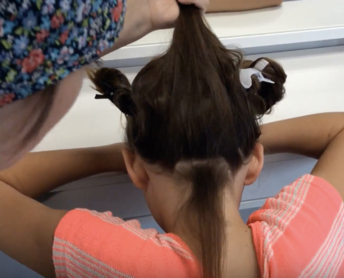LCA technician checks young girl for head lice